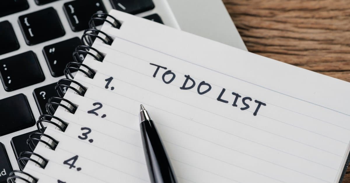 A spiral notepad features the words "To Do List" and several numbers. It sits on top of a computer keyboard.