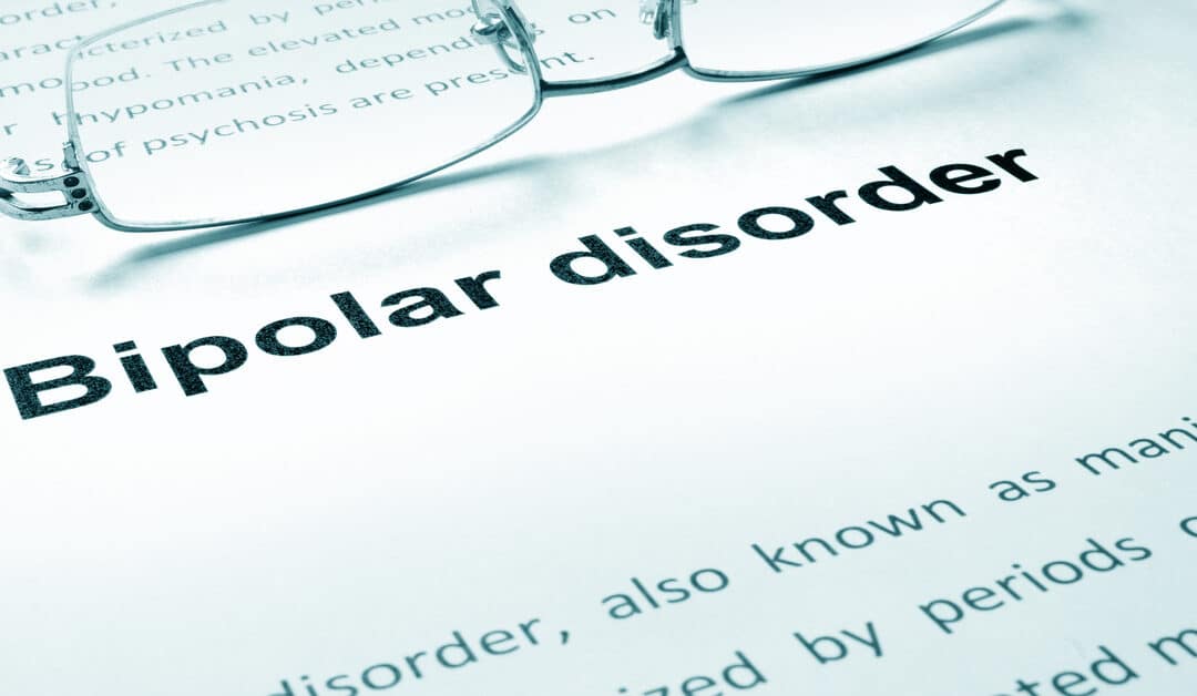 A paper has the words "bipolar disorder" printed on it and has a pair of glasses lying on it. Other text is on the paper.